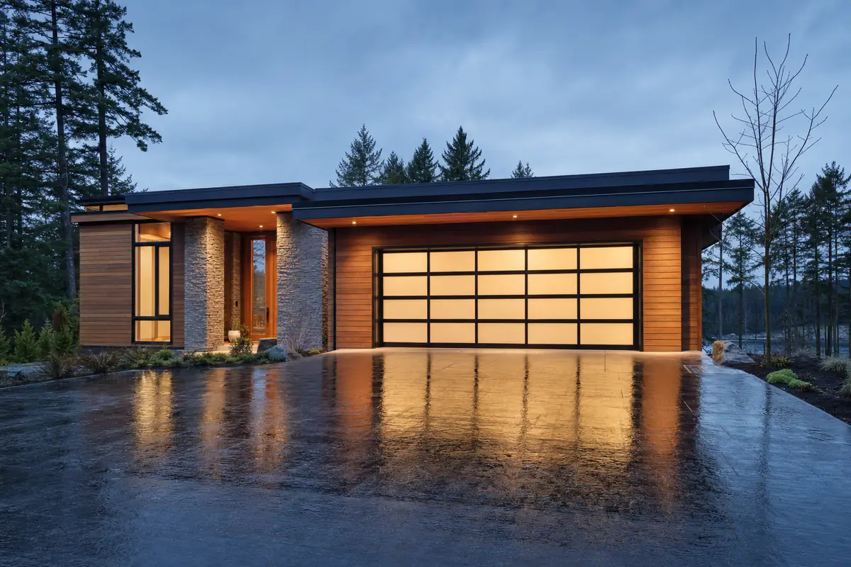 A full-view aluminium and glass garage door glowing at blue hour